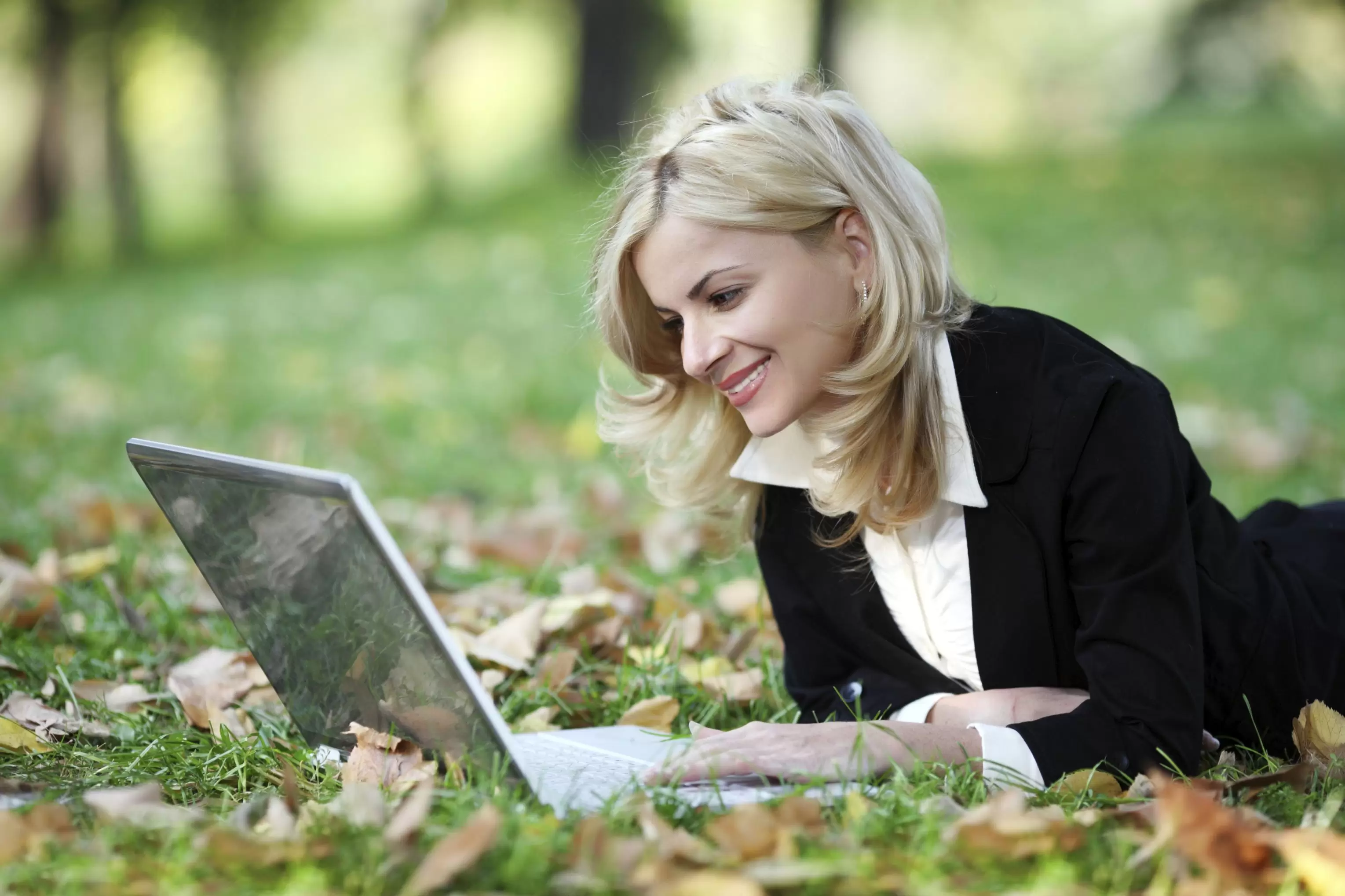 Frau im Gras mit Laptop im Waldviertel